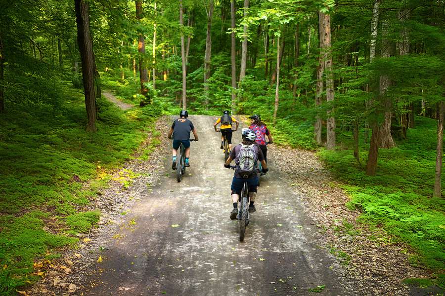 Cyclists ride up the mountain in a group in enduro mode. Two friends on the bike lift — Mont Rigaud, a ski resort offering snowboarding, alpine skiing, mountain biking, and hiking, perfect for families, in Rigaud, Quebec, near Montreal