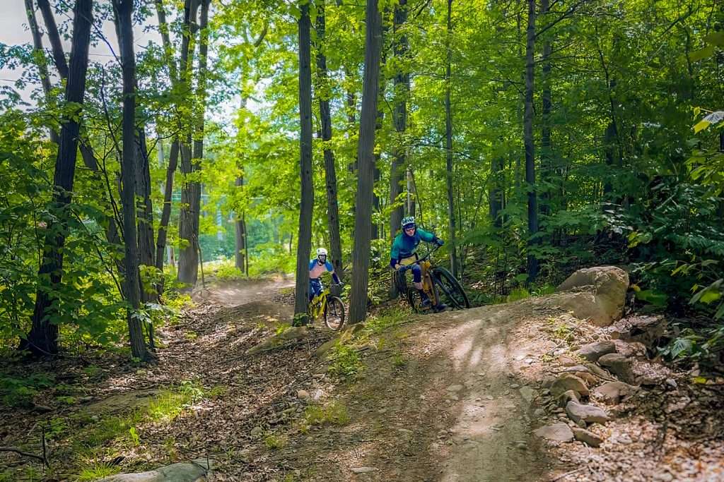 Deux cycliste de montagne se suivent sur un sentier forestier — Mont Rigaud, station de ski, planche à neige, randonnée alpine, vélo de montagne et randonnée pédestre, familiale, à Rigaud Québec, près de Montréal