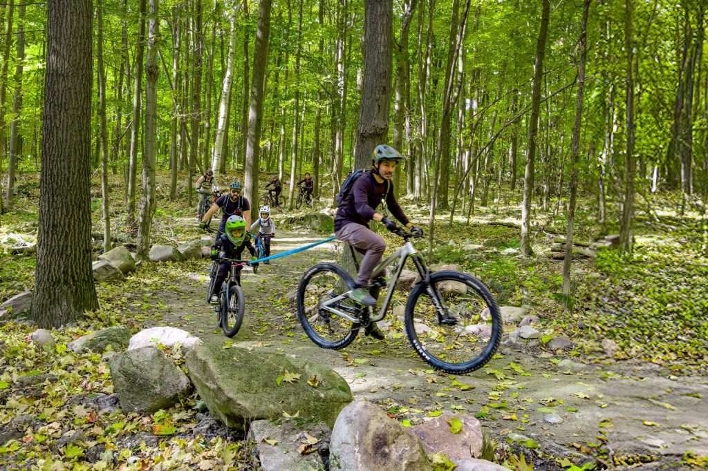 A dad tows his son on an enduro mountain bike Two trail riders descending Rigaud Mountain Two friends on the bike lift — Mont Rigaud, a family-friendly resort offering skiing, snowboarding, alpine hiking, mountain biking, and hiking in Rigaud, Quebec, near Montreal